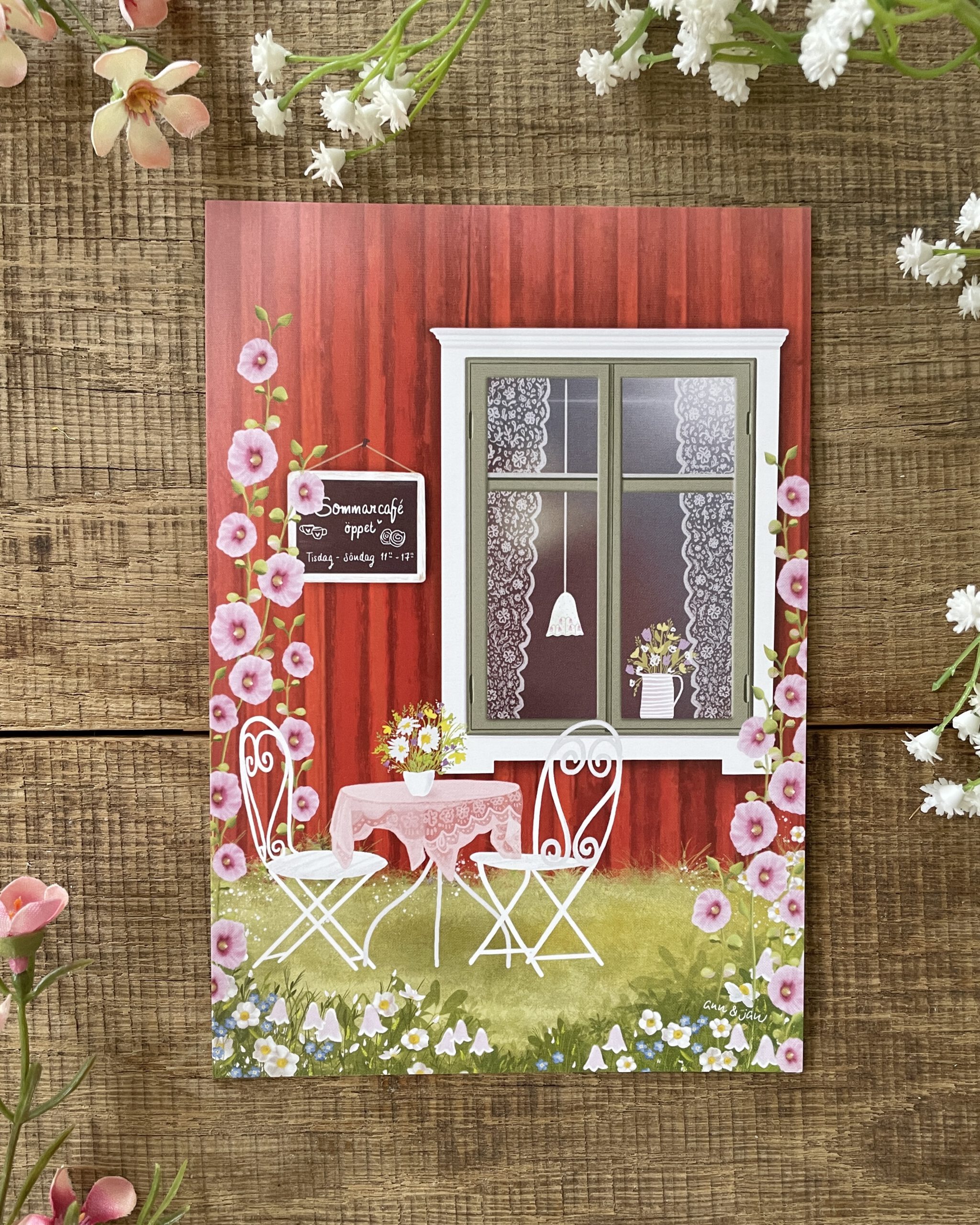 Postkarte Sommarcafé Detailansicht Tisch Stühle Stockrosen Wildblumen handillustriert Ann und Jan