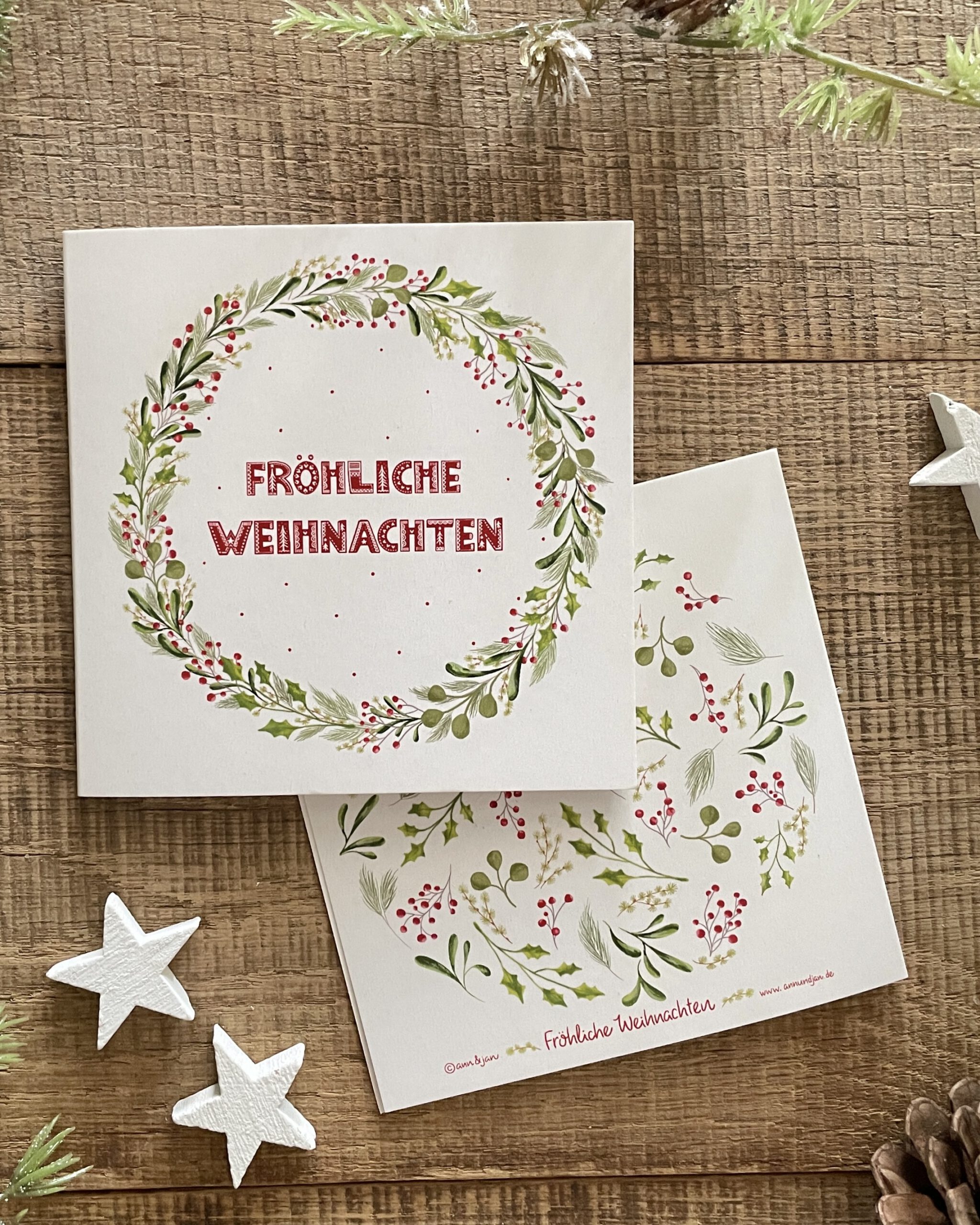 Handillustrierte quadratische Weihnachtsklappkarte Fröhliche Weihnachten Kranz grüne Blätter rote Beeren Vorderseite und Rückseite von Ann und Jan