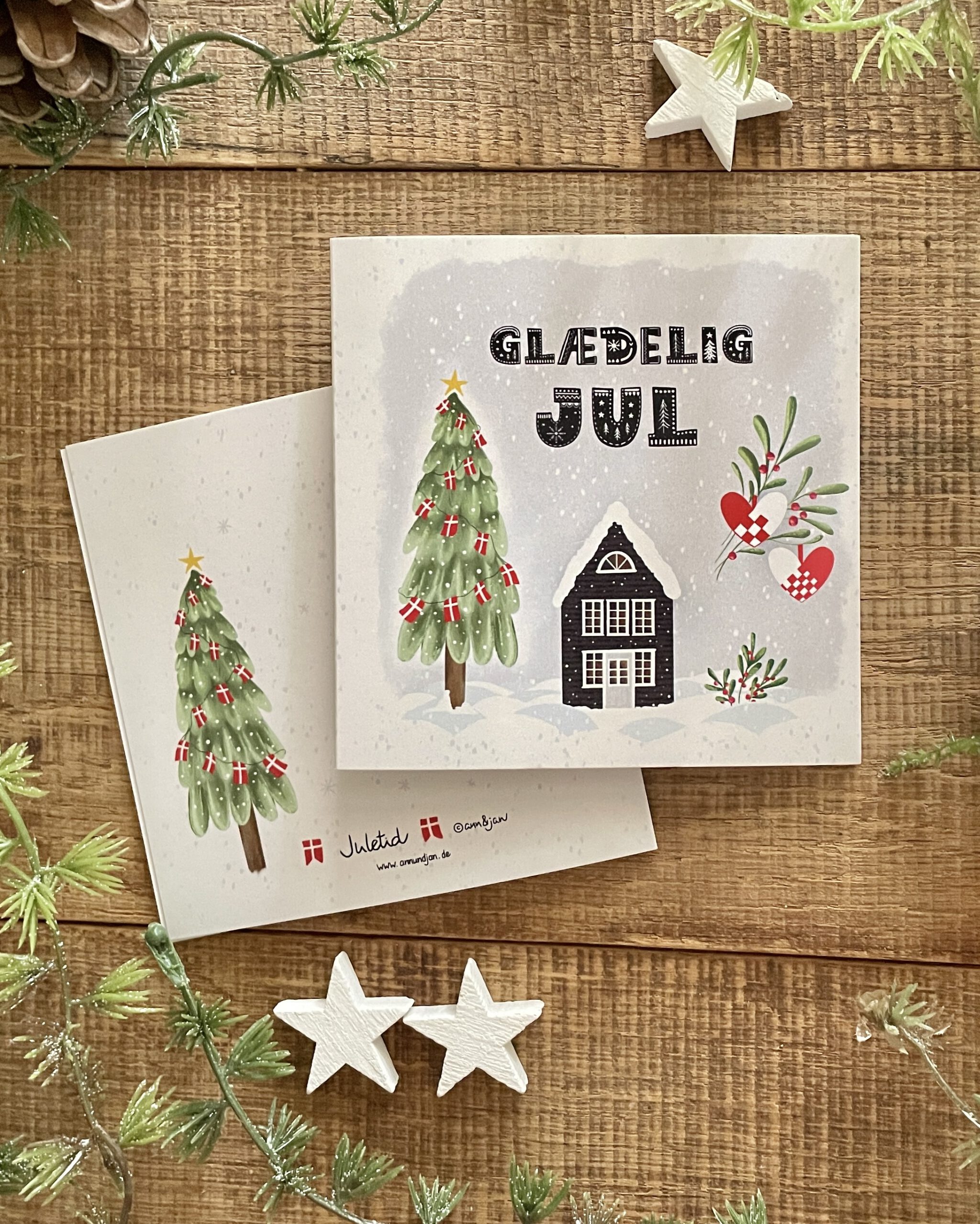 Handillustrierte quadratische Weihnachtsklappkarte Juletid schwarzes Holzhaus Tannenbaum dänische Flaggen Julehjerter von Ann und Jan