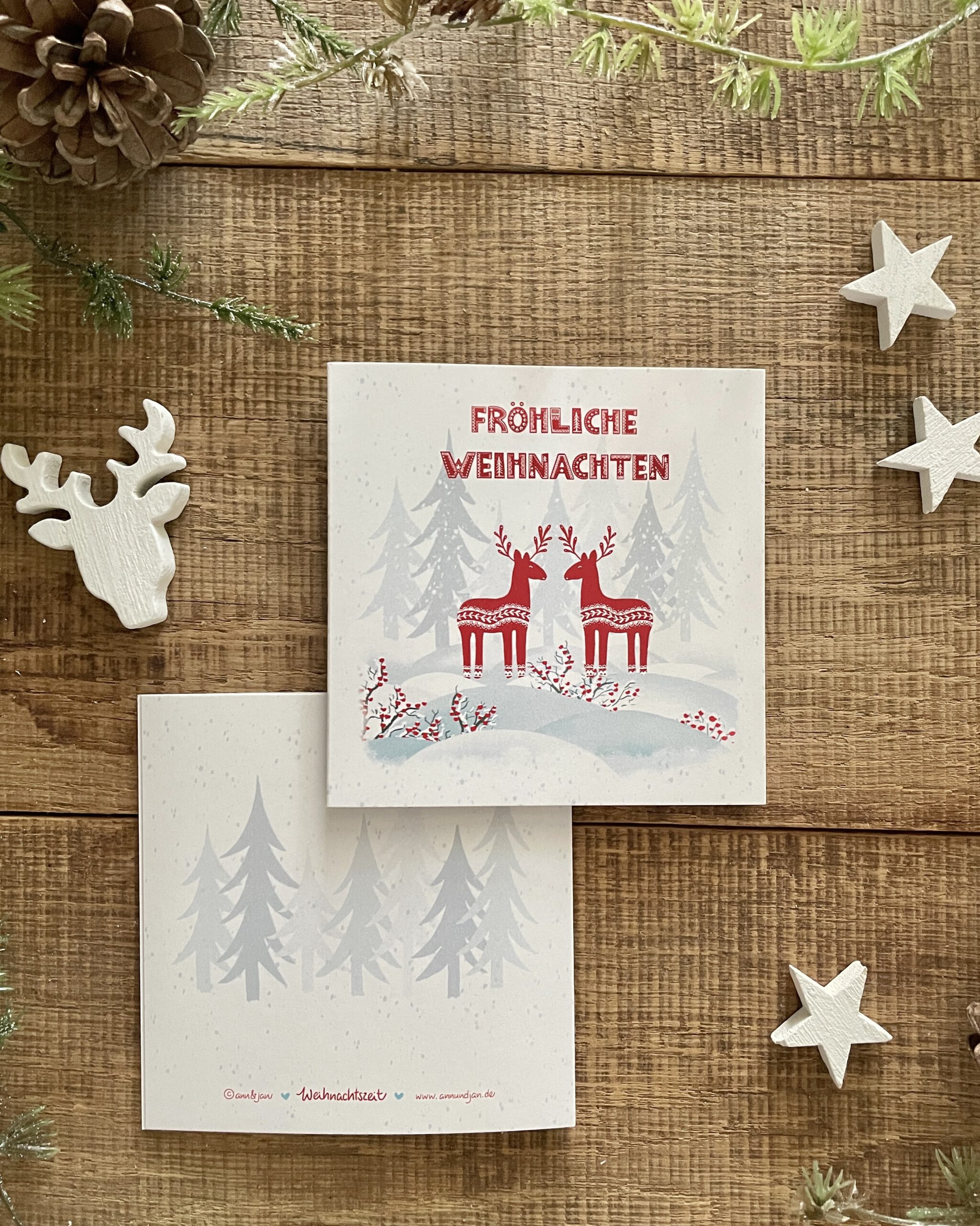 Handillustrierte quadratische Weihnachtsklappkarte Weihnachtswald zwei rote Hirsche Winterwald Fröhliche Weihnachten von Ann und Jan