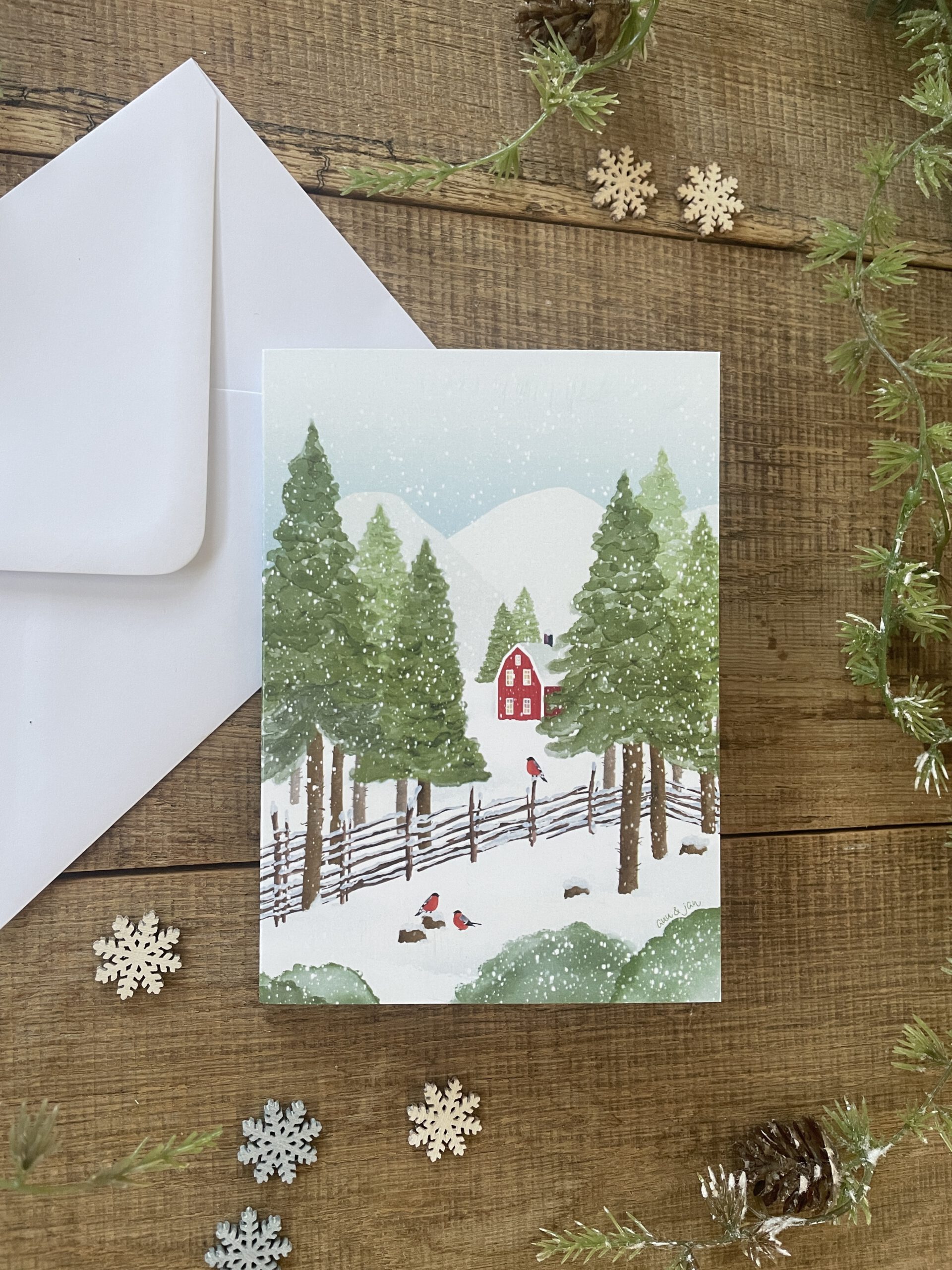 Handillustrierte Klappkarte Winterglück rotes Holzhaus verschneite Berglandschaft Gimpel Tannen von Ann und Jan Kuvert weiß