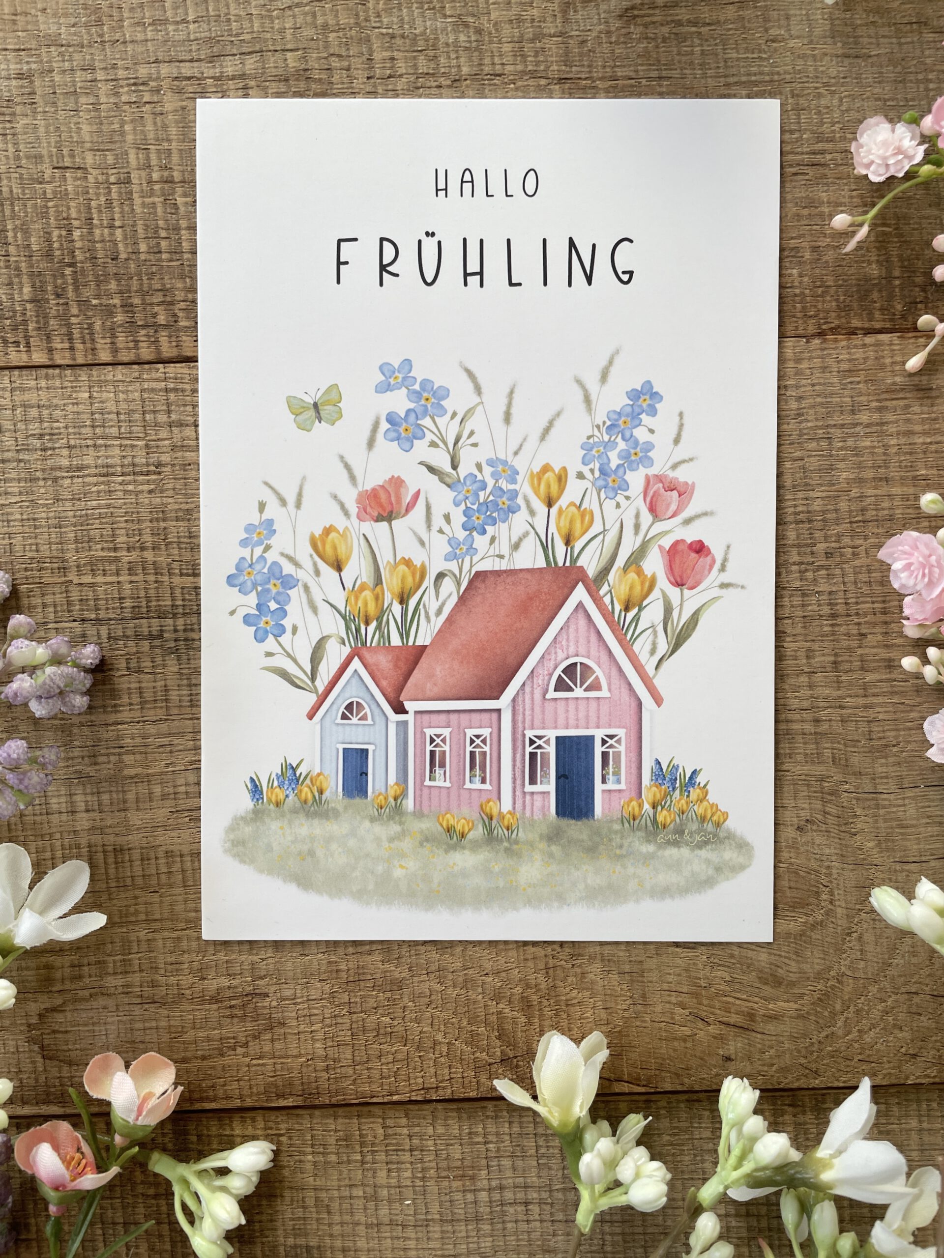 Handillustrierte große Postkarte Hallo Frühling bunte Holzhäuser Vergissmeinnicht Krokusse Tulpen Schmetterling von Ann und Jan