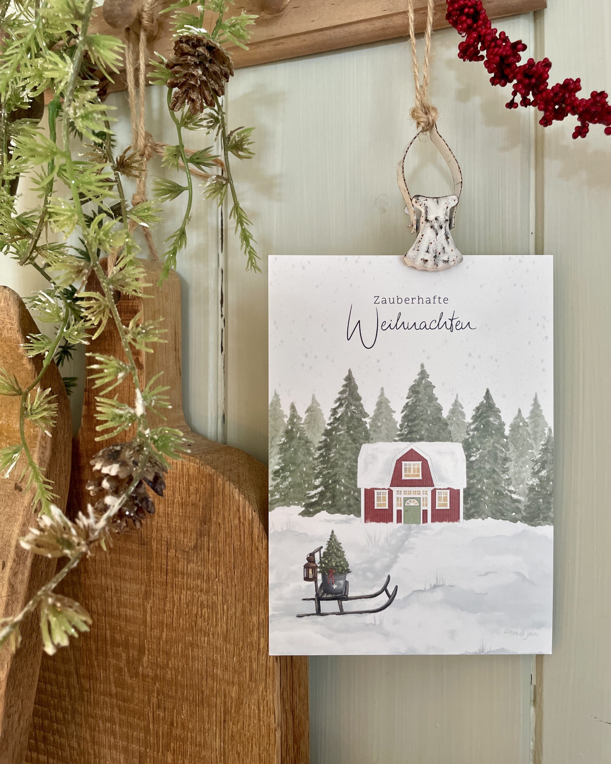 Postkarte Zauberhafte Weihnachten. Schwedenhaus mit Schlitten und Weihnachtsbaum in verschneiter Landschaft.